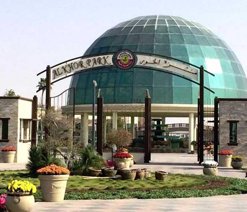 Green open space at Al Khor Park with families, play areas, animals, and palm trees on a bright, clear day.