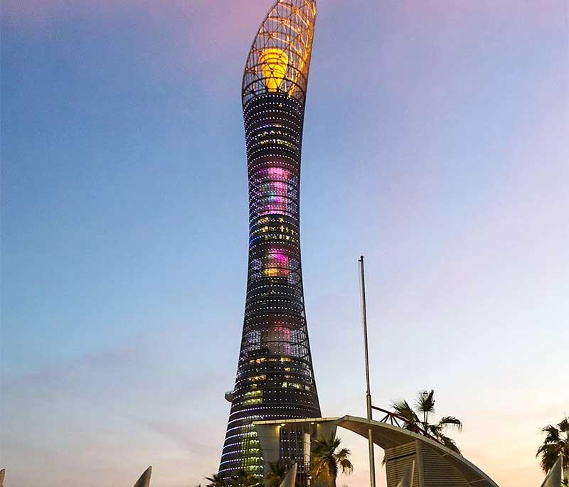 Tall Aspire Tower (The Torch) with sleek design and lights spiraling around the structure against the night sky.