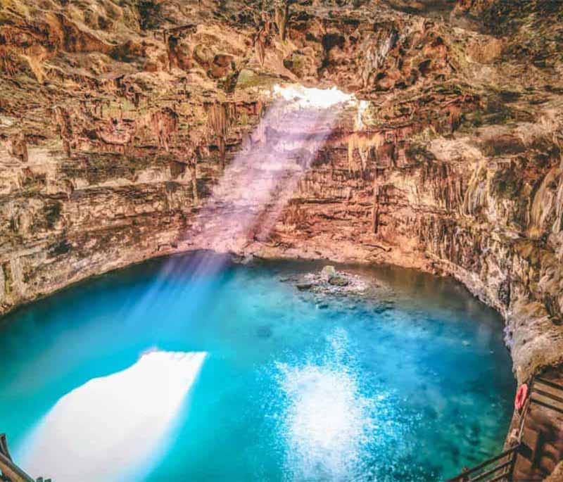 Cenote Samula, Yucatan - Famous for dramatic light beam shining through cave roof, illuminating clear waters.