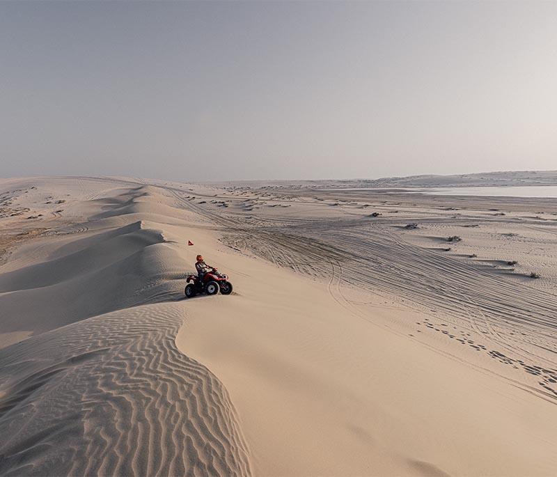 Dunes and 4x4 vehicles in motion during a desert safari in Khor Al Adaid with golden sand and adventure seekers.