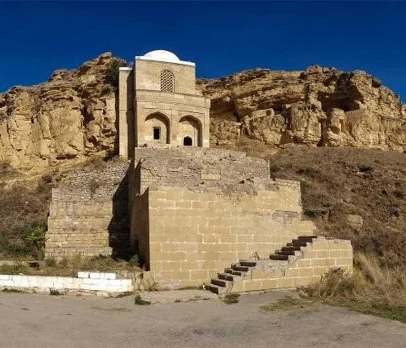 Diri Baba Mausoleum, Maraza, featuring a two-storey mausoleum embedded in a cliff face, revered as a holy site.