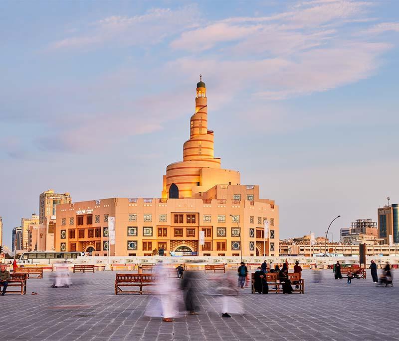 Fanar Islamic Center with spiral minaret lit at dusk, casting a glow over the cultural district of Doha.
