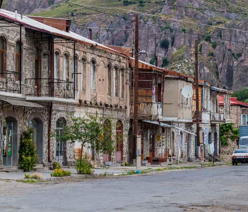 Goris, showcasing dramatic stone formations and traditional cliffside homes in a quaint town setting.