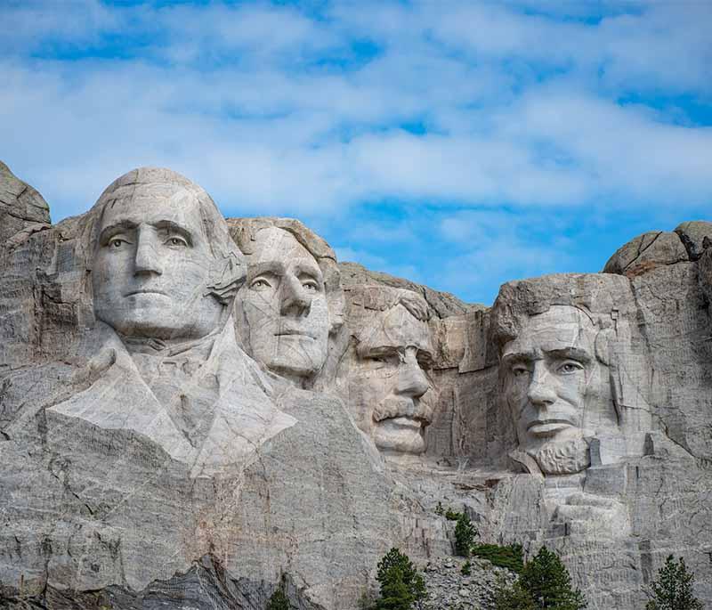 Mount Rushmore: Monumental sculpture with faces of four US presidents carved into granite rock surfaces.