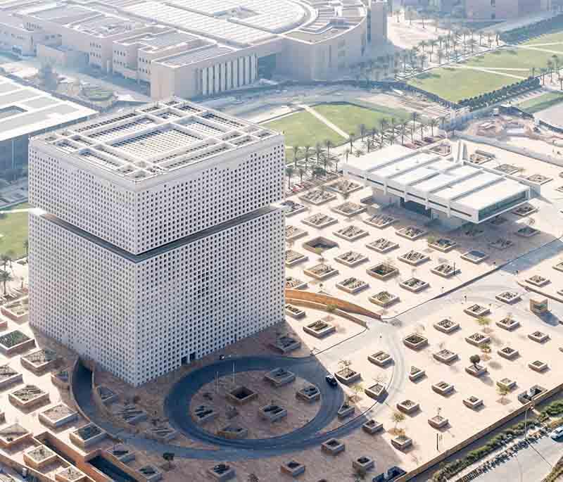 Modern Qatar Foundation campus buildings with students walking, glass facades, and educational banners.