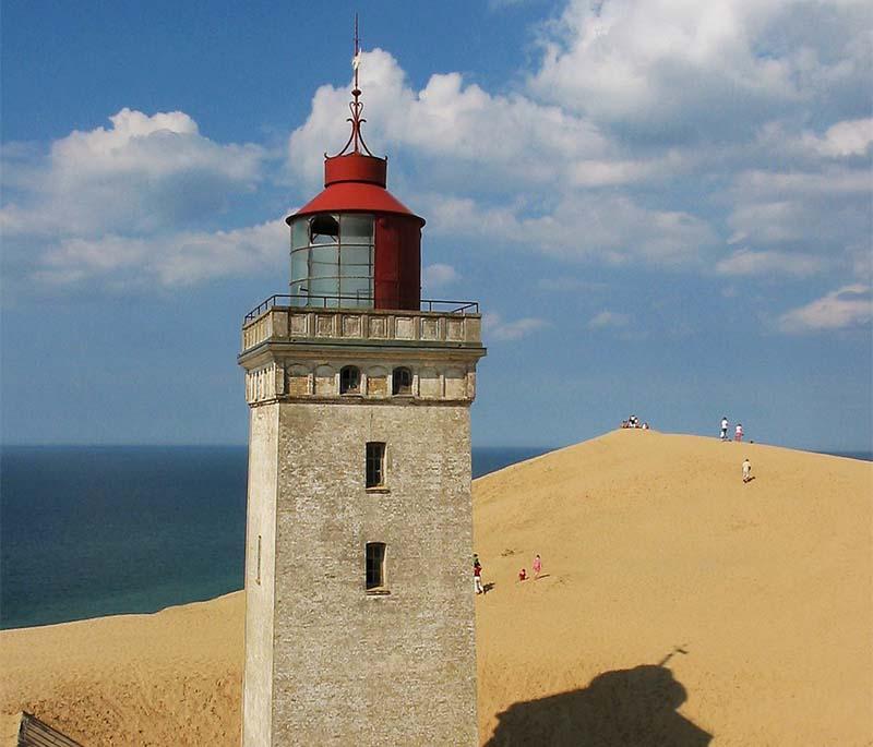 Rubjerg Knude Lighthouse, a dramatic lighthouse partially buried in sand dunes, offering spectacular views of the North Sea.