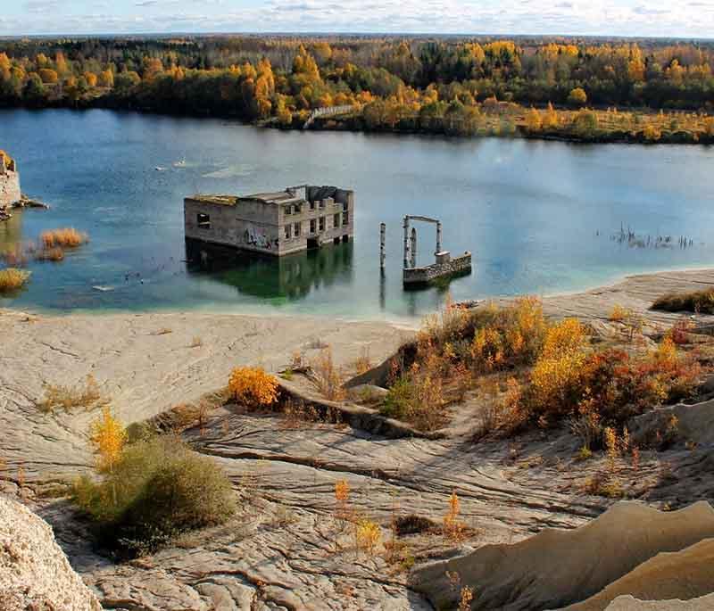 Rummu Quarry, abandoned site turned unique swimming spot with clear blue waters, submerged buildings.