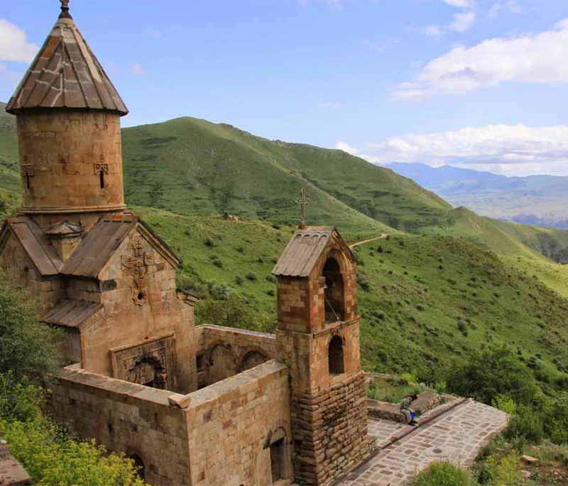 Spitakavor Monastery, featuring a remote medieval monastery with intricate stone carvings set against forested hills.