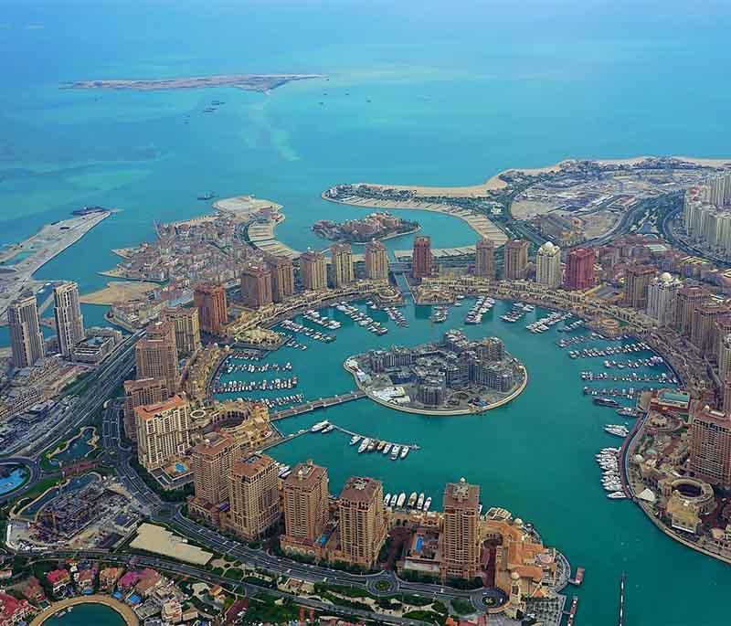 Waterfront view of The Pearl-Qatar with luxury yachts, pastel towers, and boutique cafés along the promenade.